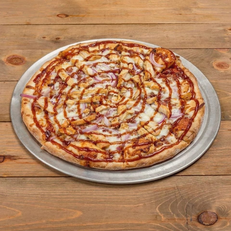 BBQ chicken pizza with red onions and a swirl of BBQ sauce on a wooden table.