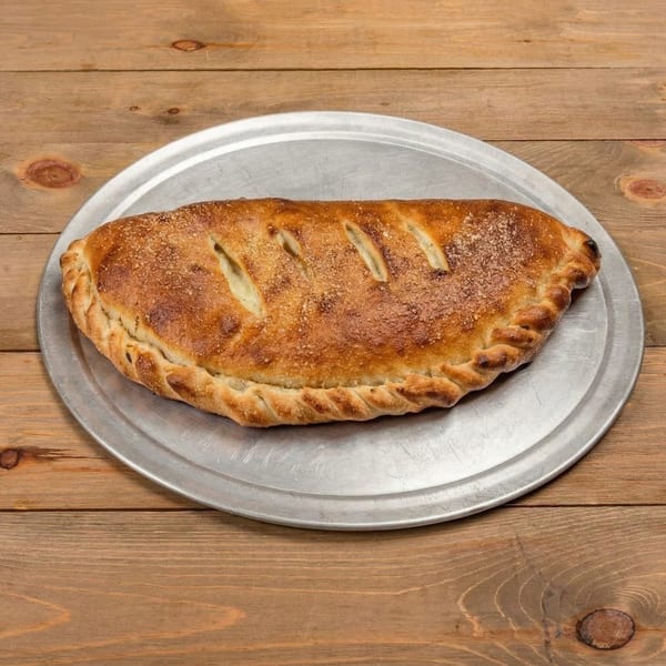 A golden-brown calzone with a braided crust and parmesan dusting, on a metal pizza pan.
